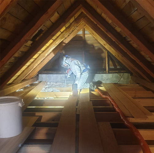 Praconik dokonujący ocieplania strychu pianą PUR